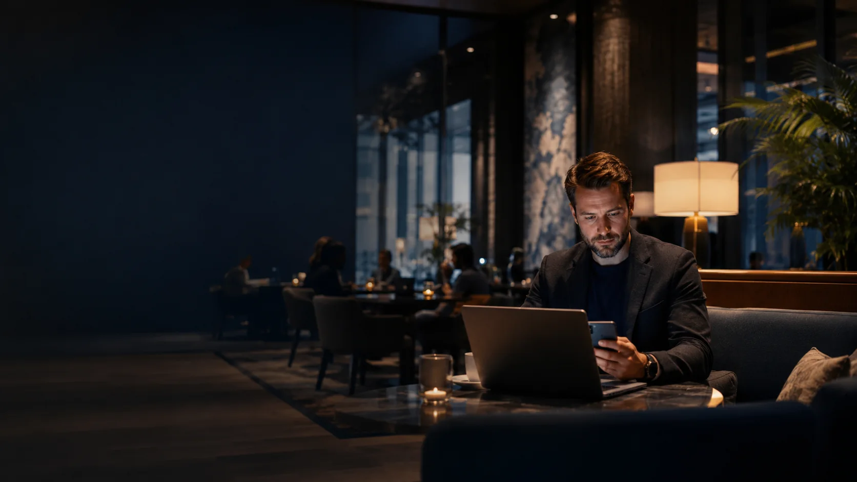 Traveller using a laptop and phone in a public lounge
